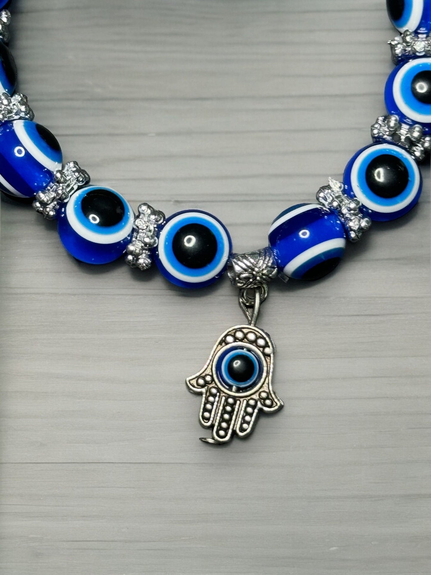 A close up photo of the metal hamsa hand charm on the bracelet.