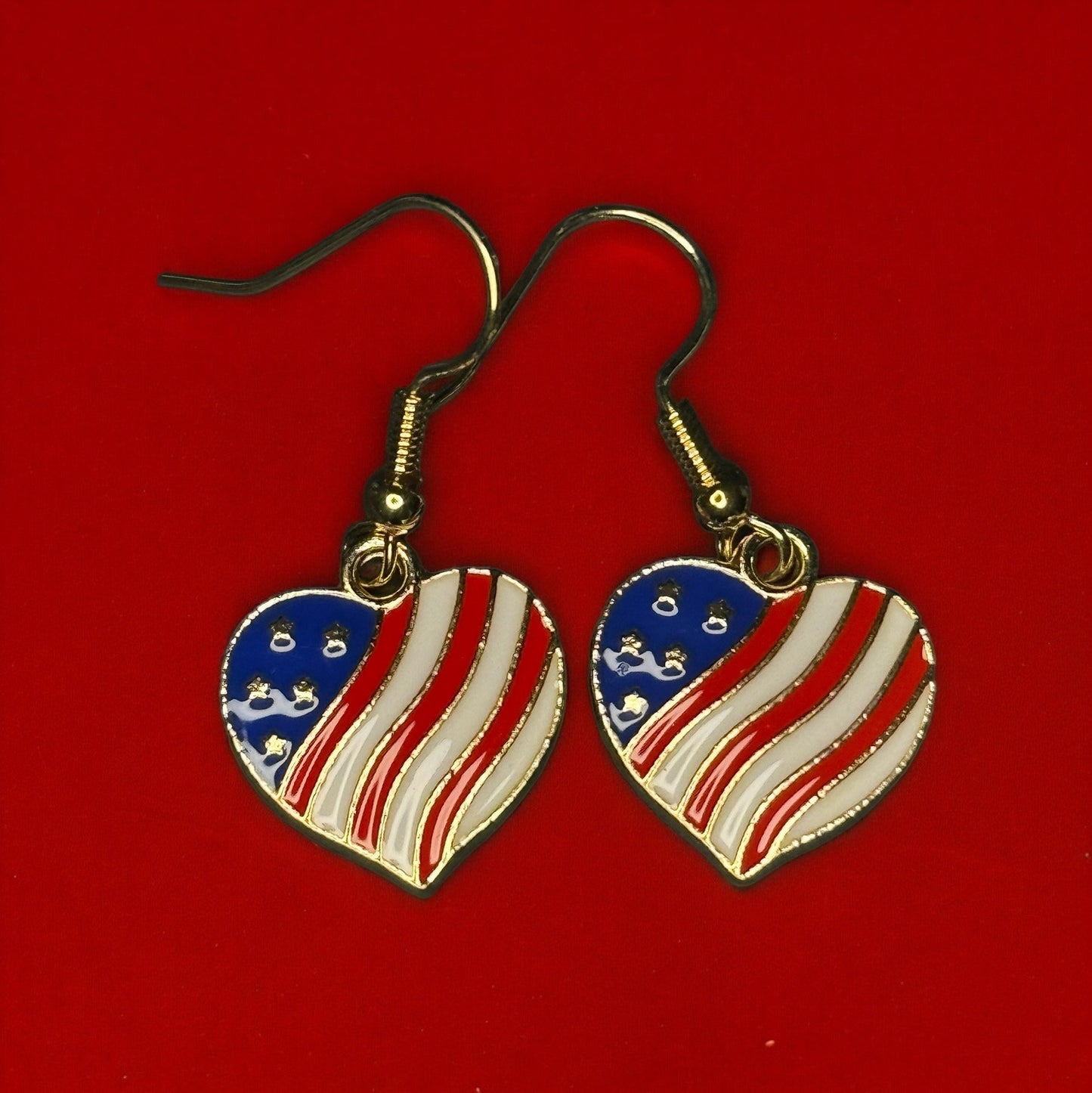 One pair of enamel dangle earrings shaped like hearts and colored like the USA flag.