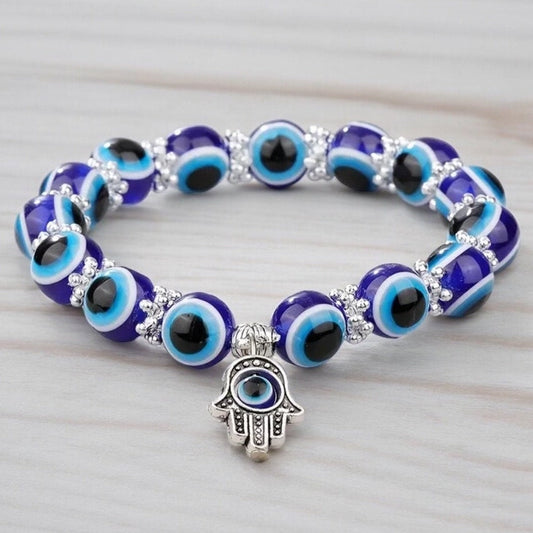 A beaded bracelet with blue evil eye beads and a metal hamsa hand charm in the middle.