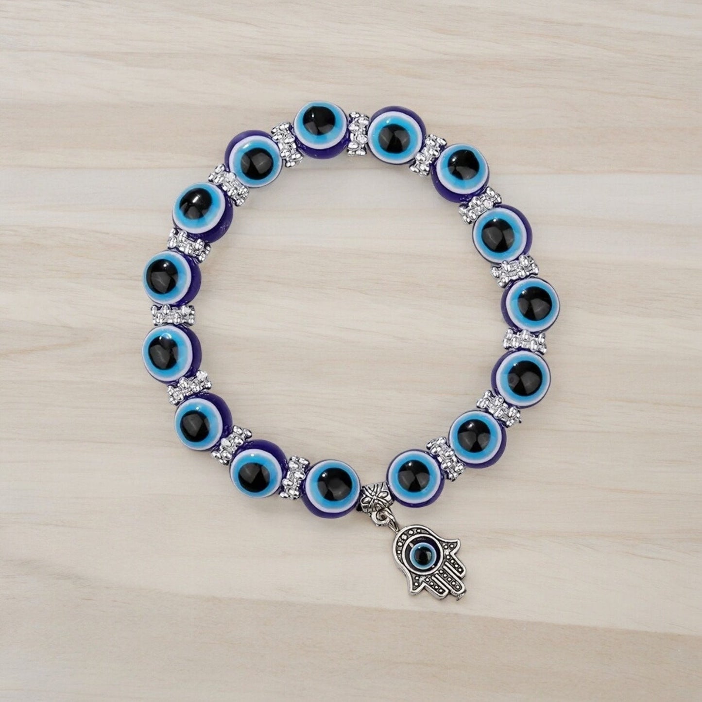 Blue beaded evil eye Hamsa hand bracelet laying on a wooden countertop.