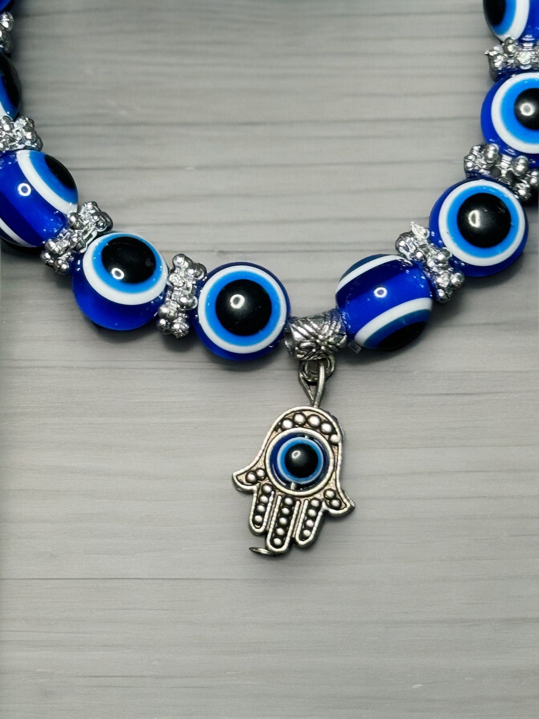 A close up photo of the metal hamsa hand charm on the bracelet.