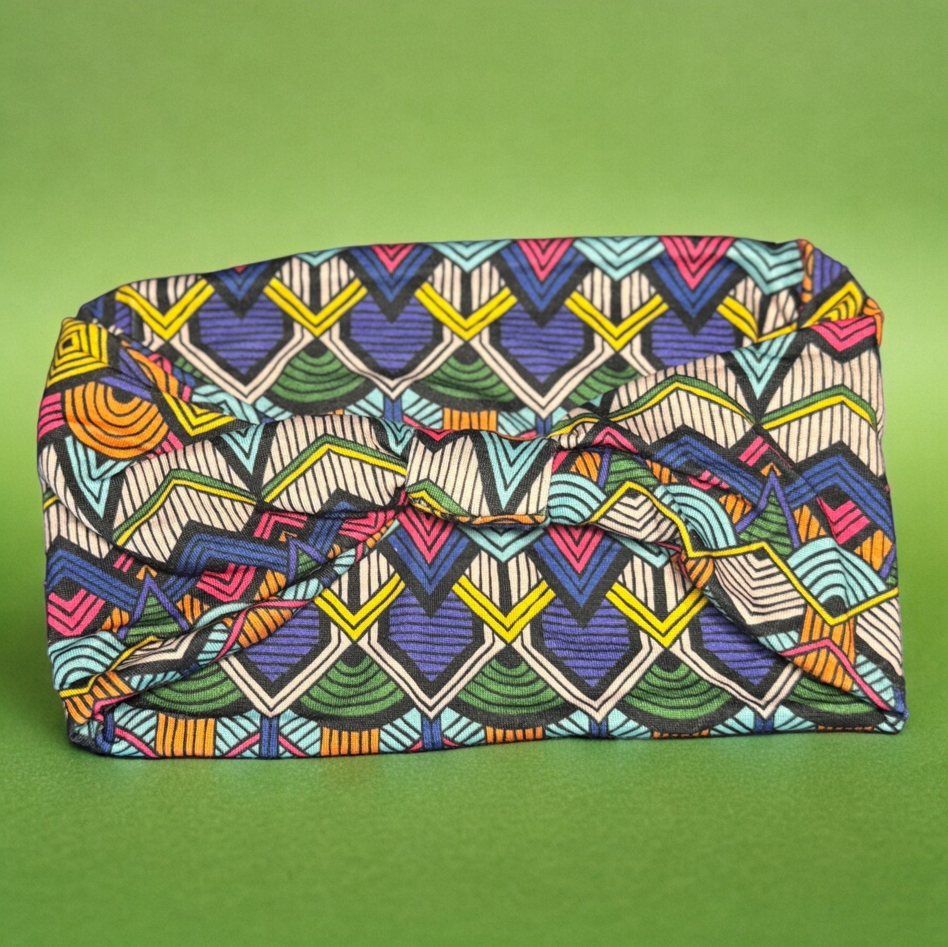 The backside of a stretchy polyester blue African tribal print headband. The print is more artistic and the photo displays a knotted side of the headband.