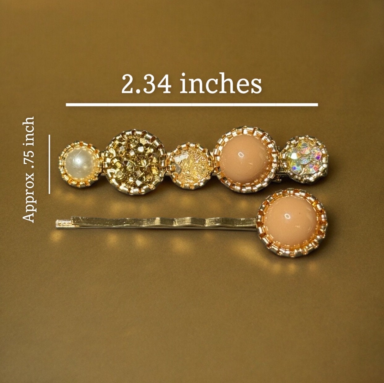 The peach set of bling barrettes laying on a gold surface with measurements reading 2.34x.75in