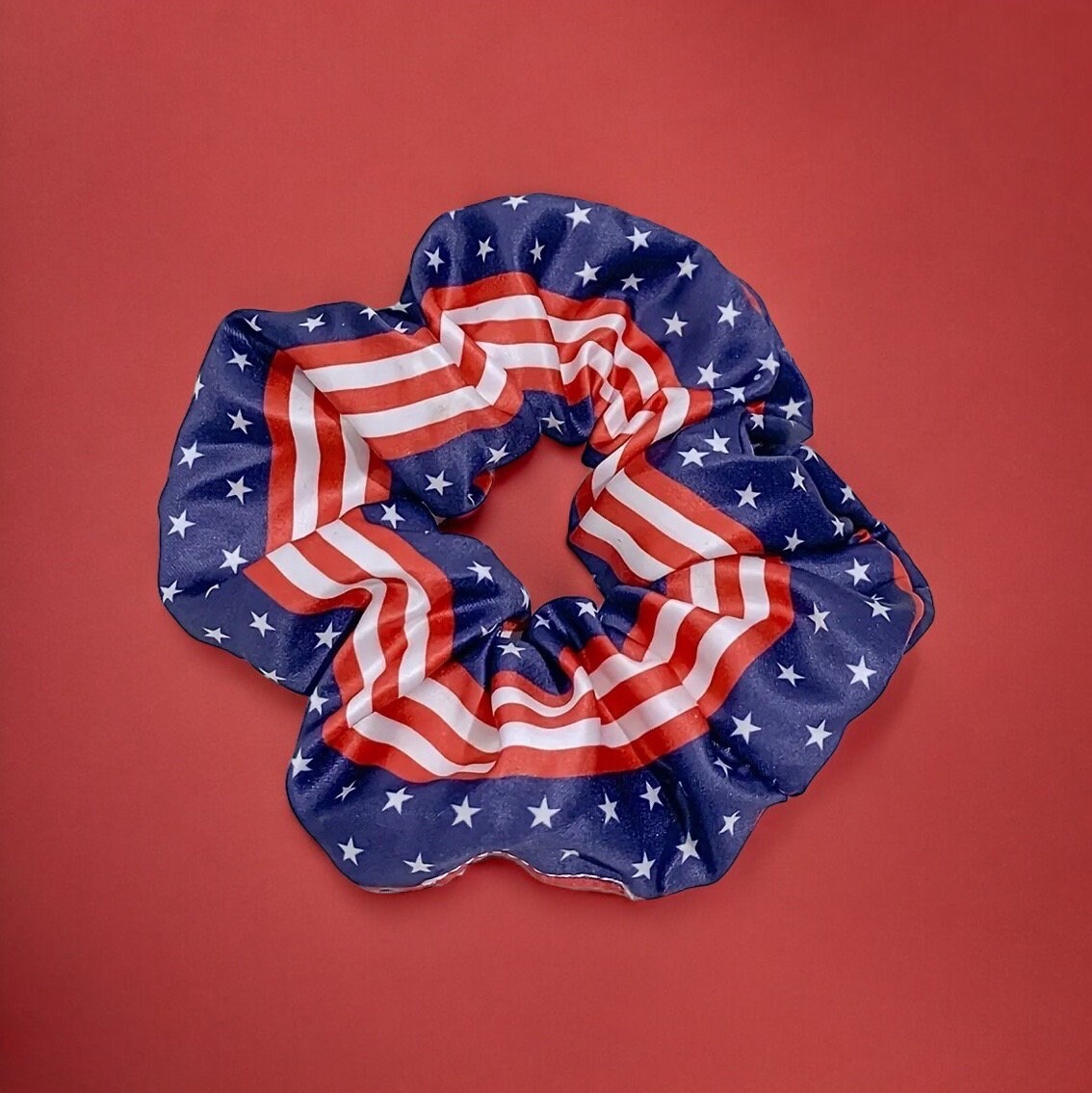 One scrunchie that is primarily a rich blue with white stars and some red and white stripes in the center.