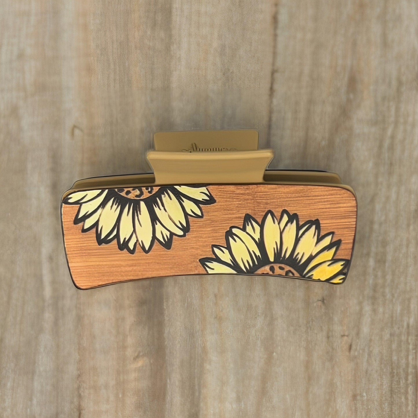 A tan colored medium square shaped faux leather claw clip with two yellow sunflowers on it.