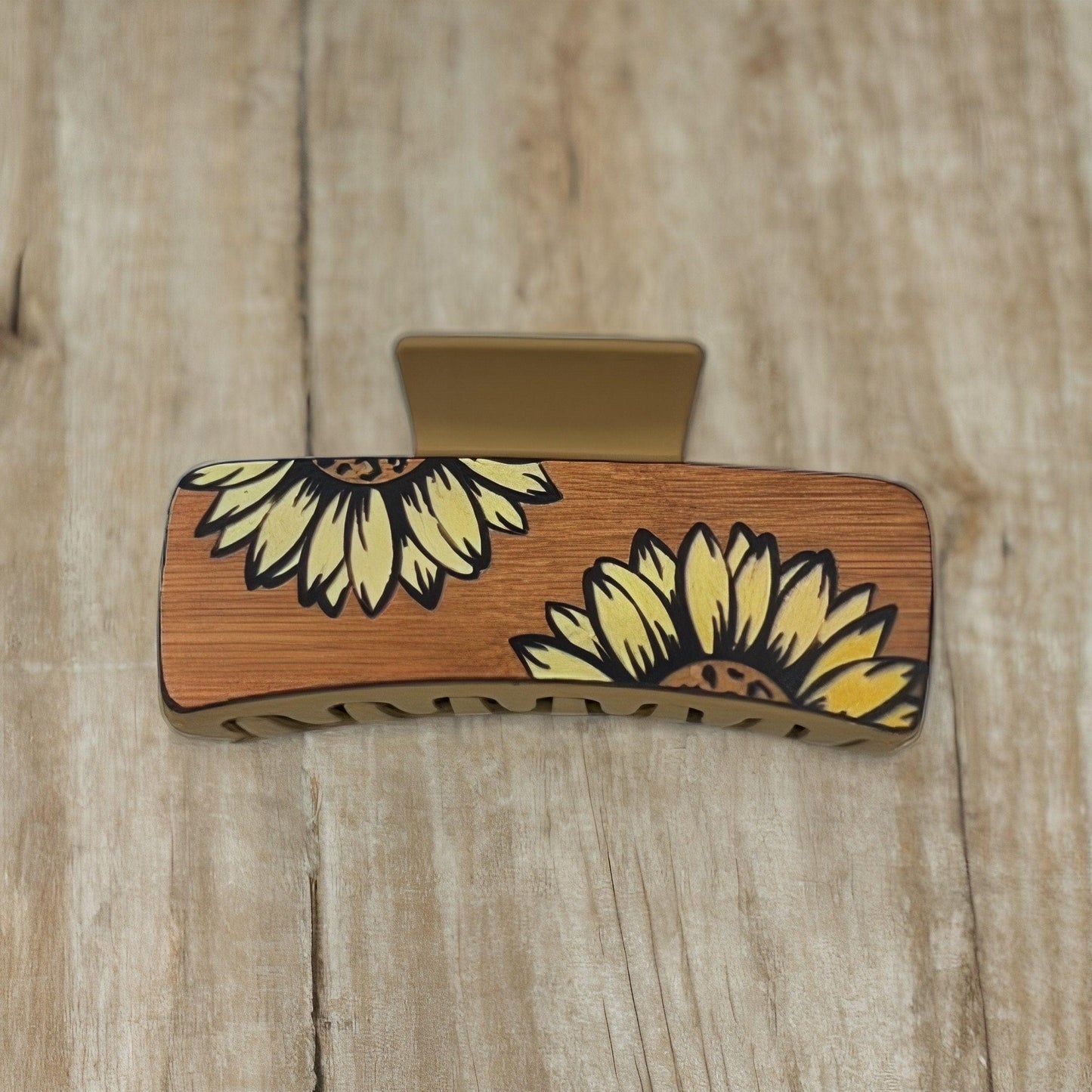 A tan colored medium square shaped faux leather claw clip with two yellow sunflowers on it.