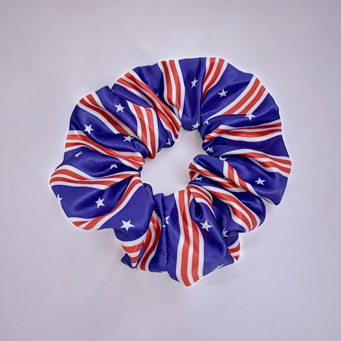 One scrunchie with blue and red stripes. The blue contains some white stars and the red contains some white lines.