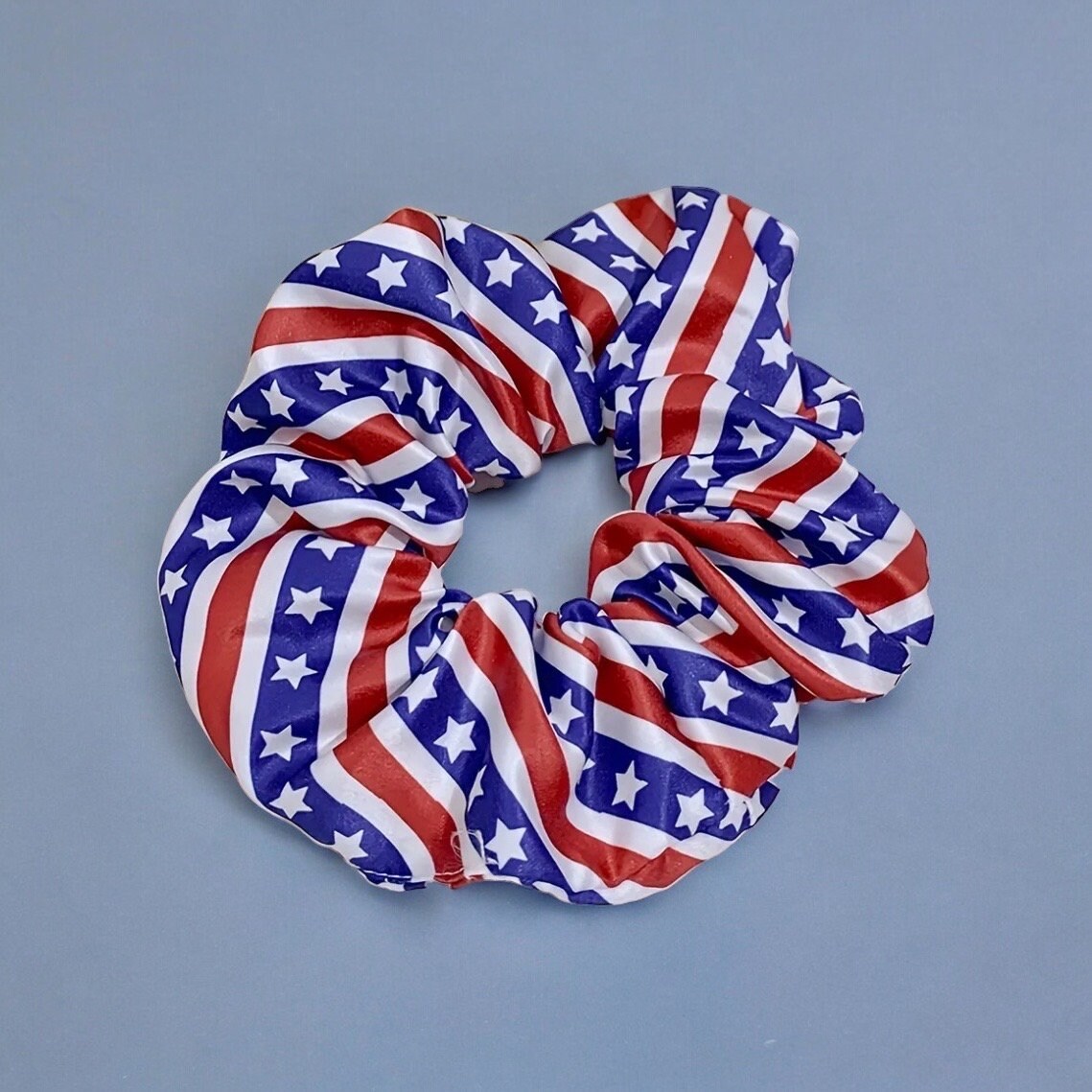 One scrunchie with bold red and white lines and thick blue lines with white stars on stop.